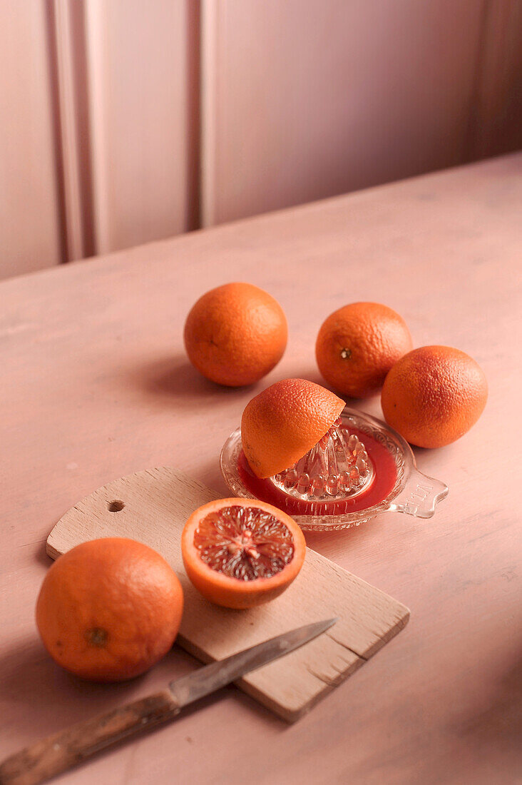 Blood oranges with a juicer on a table