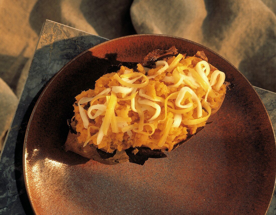 Baked Potato (Süsskartoffel) mit Käse auf braunem Teller