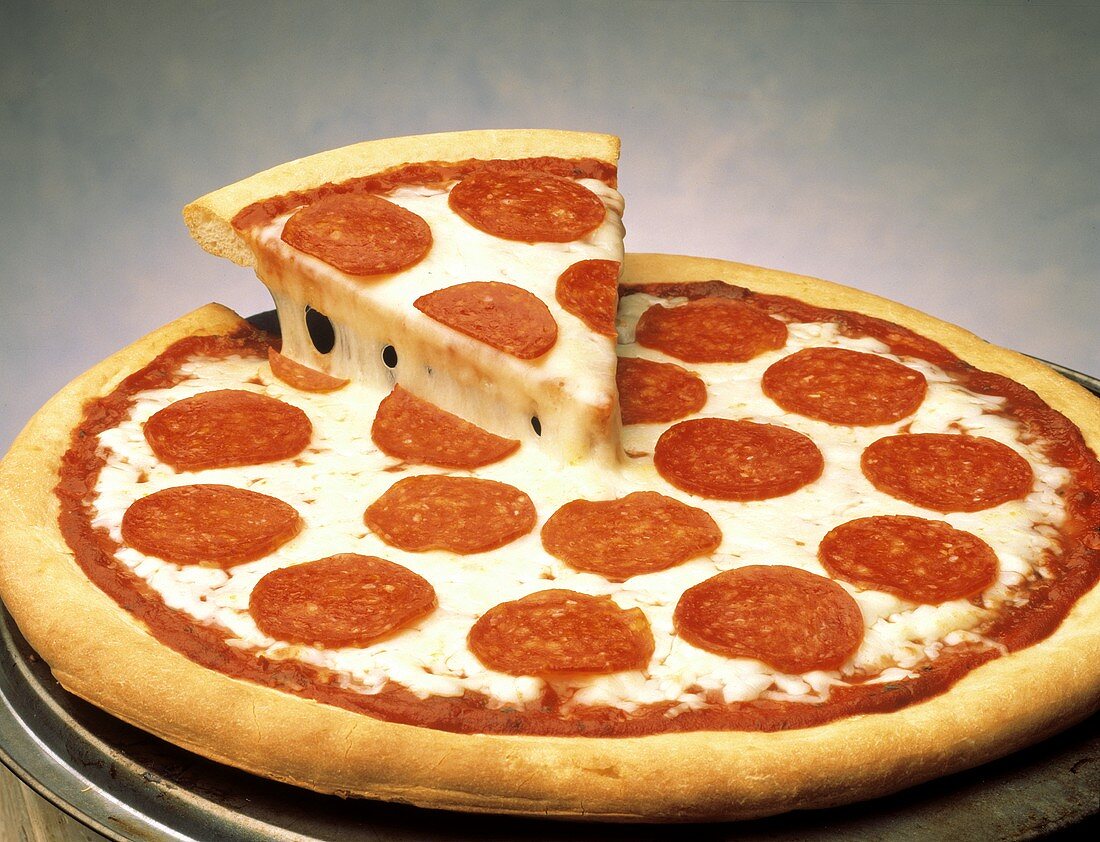 Round Pepperoni Pizza with Slice Being Lifted