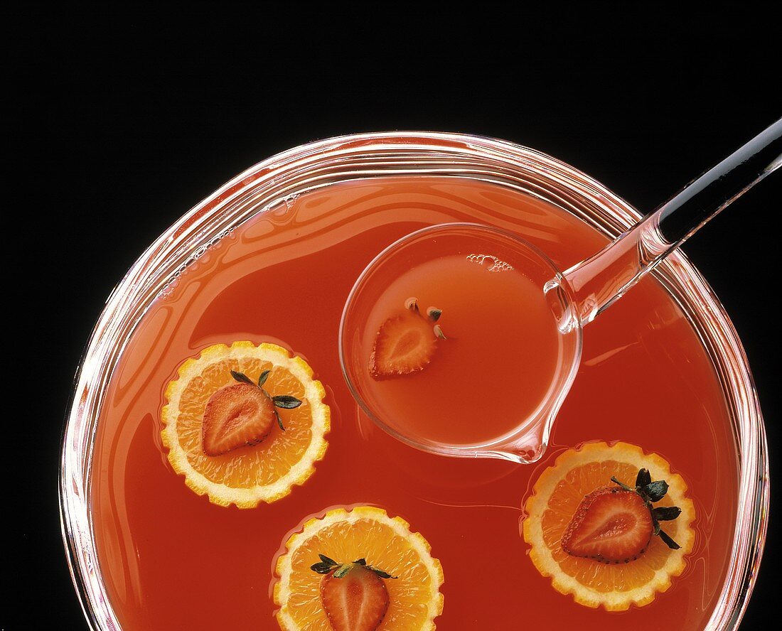 Orangen-Erdbeer-Bowle in Glasschüssel mit Kelle
