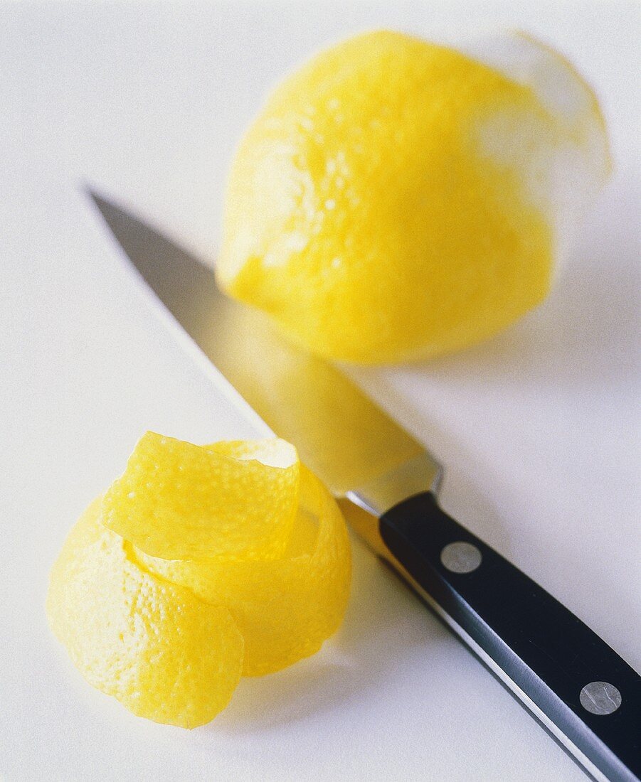 Zitronenschale, Messer und halb geschälte Zitrone