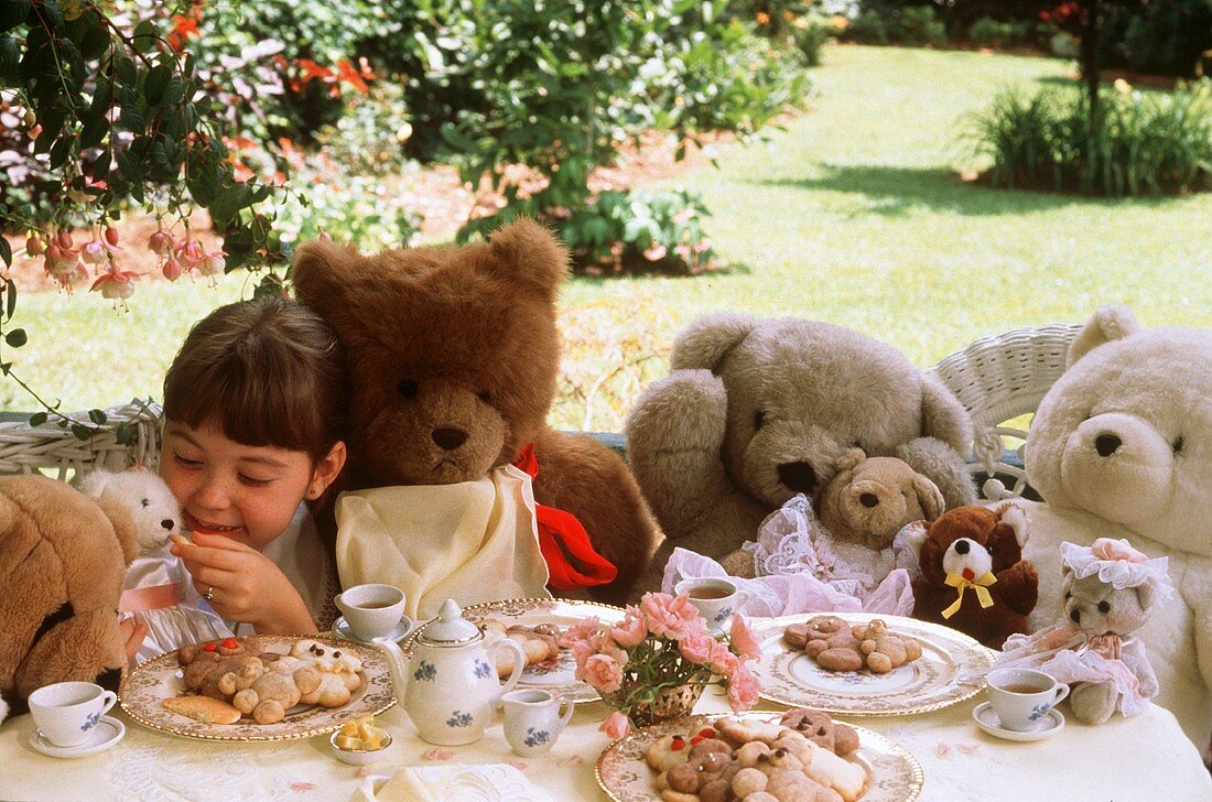 Teeparty mit Kind und vielen Teddybären im Garten