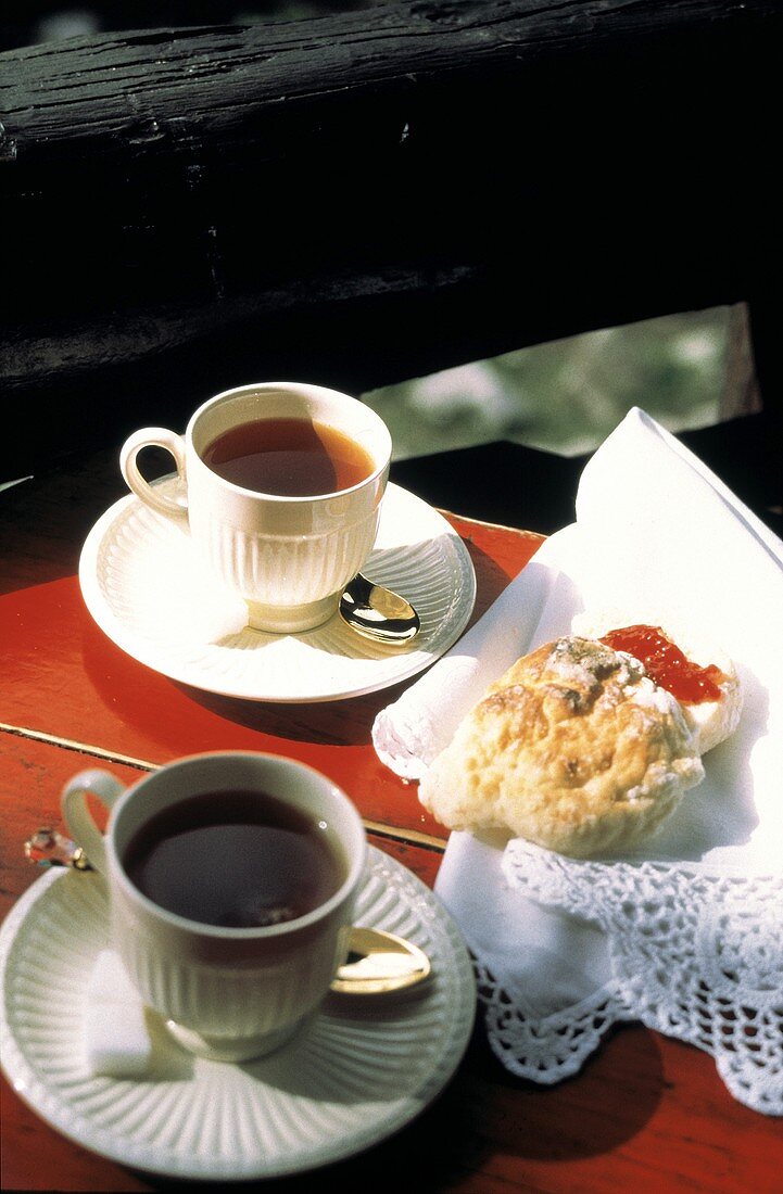 weiße Teetassen auf Tisch mit Zuckerwürfeln & Gebäck