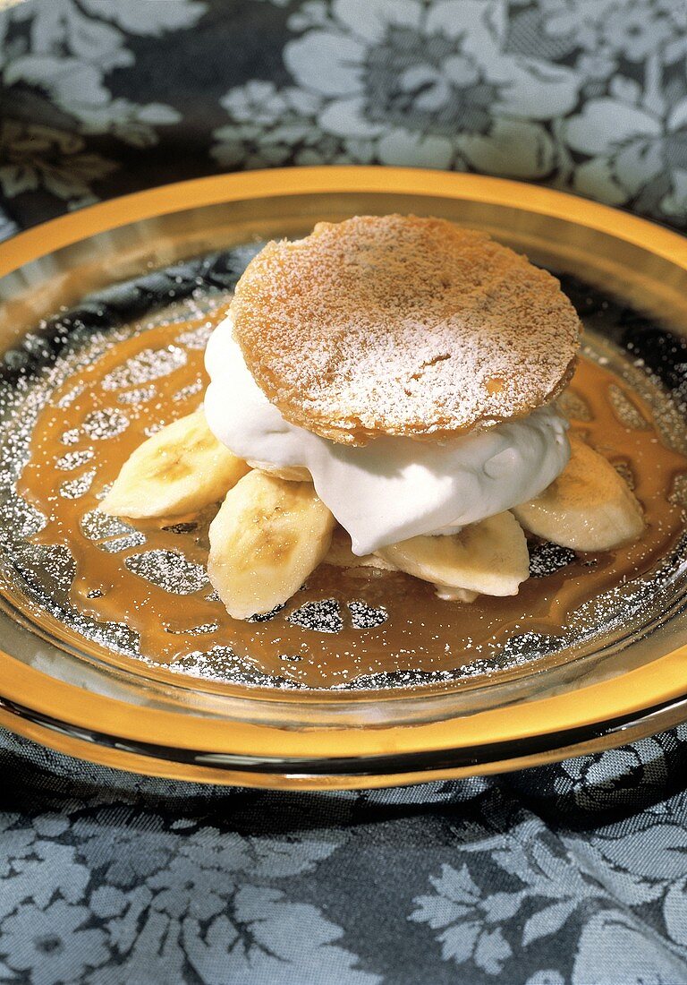 Bananas and whipped cream with a puff pastry top and caramel sauce
