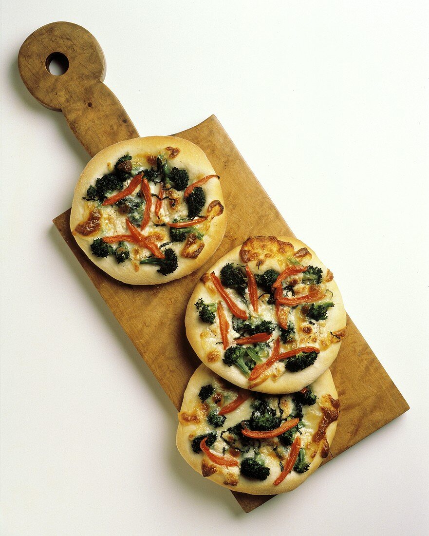 Broccoli and Red Pepper Pizzas on a Cutting Board