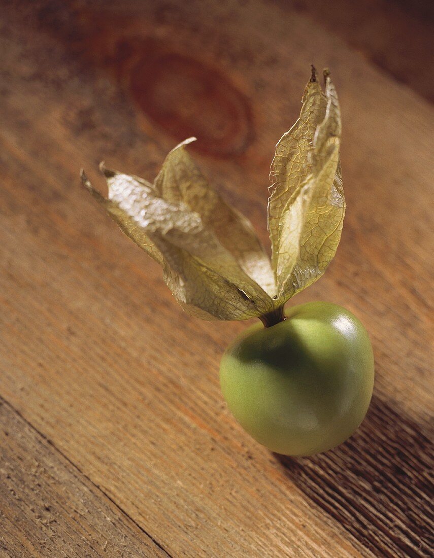 Eine einzelne Tomatillo auf Holzuntergrund