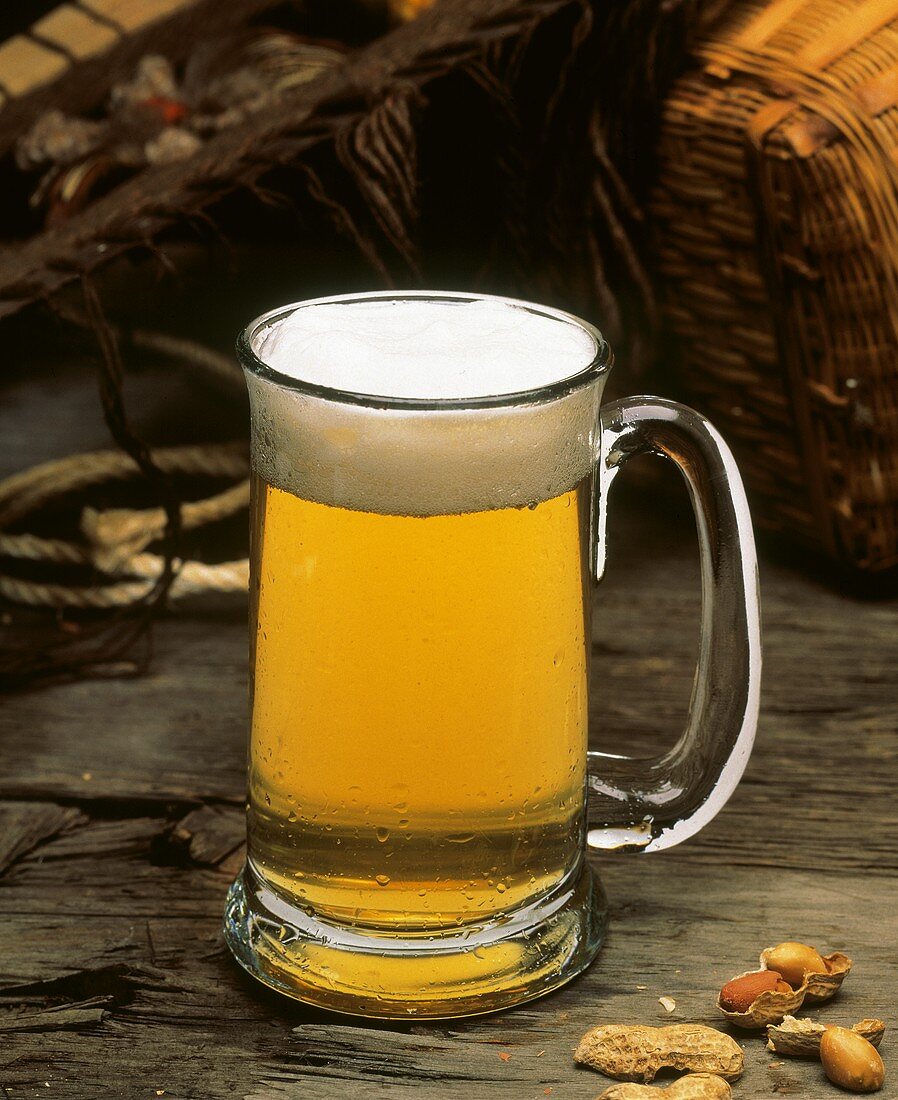 Ein Glaskrug Bier auf Holz mit einigen Erdnüssen