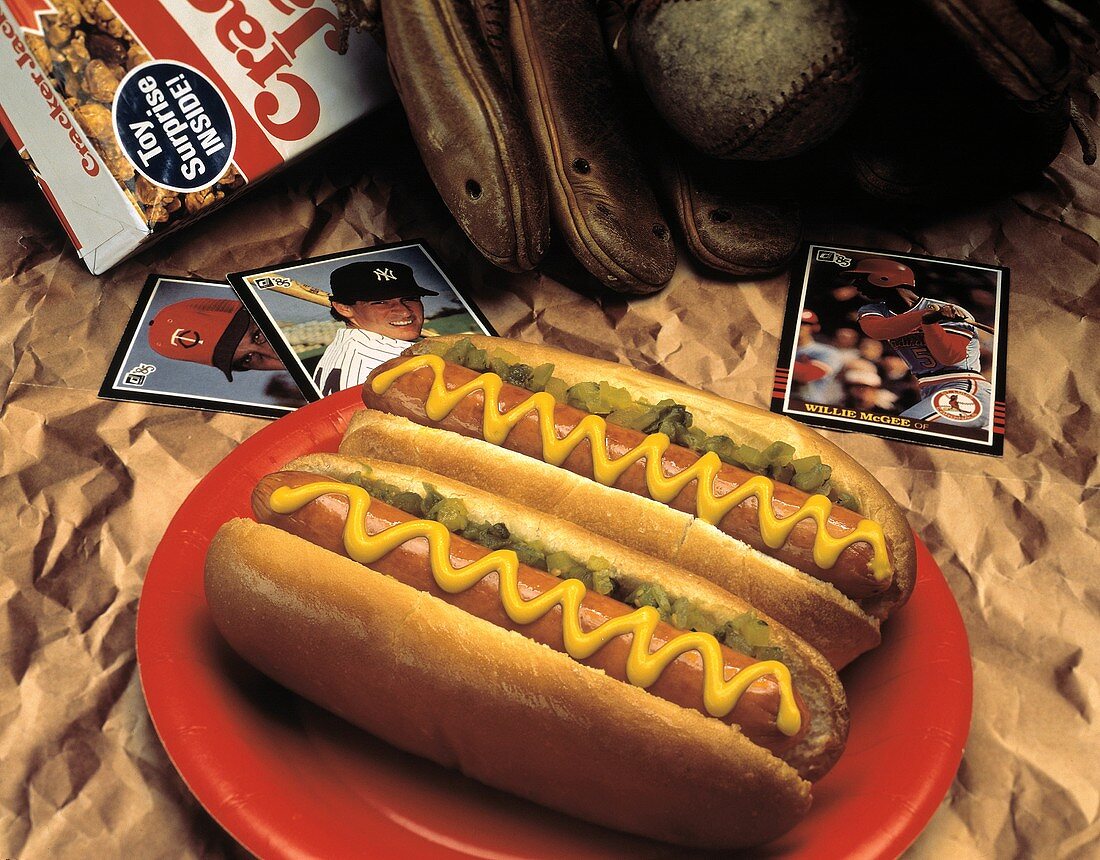 Zwei Hot Dogs mit Senf auf rotem Plastikteller