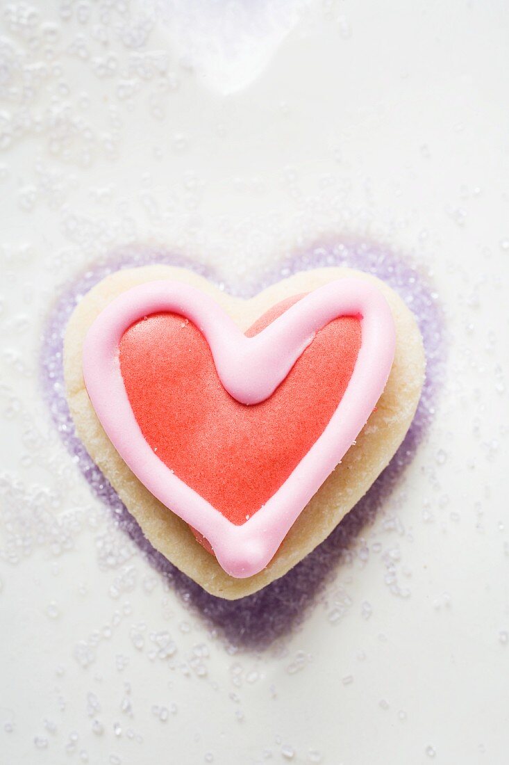 A red and white, heart-shaped marzipan biscuit with sugar