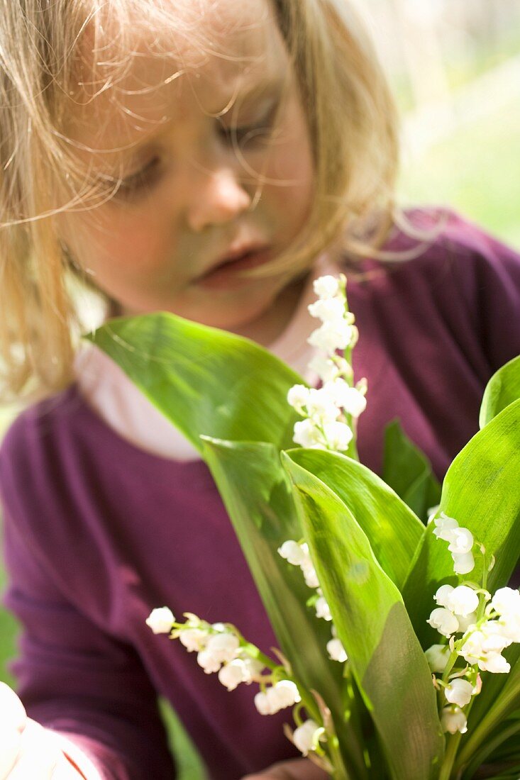 A little girl holding a bunch of lily of the valley