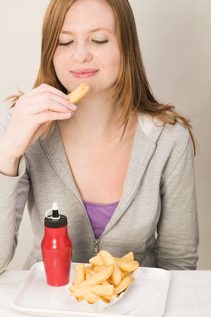 Junge Frau isst Pommes frites