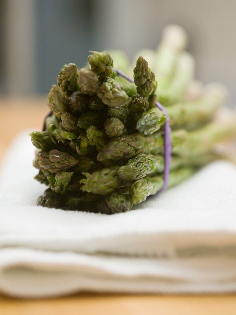 A bunch of green asparagus on a white cloth (close-up)