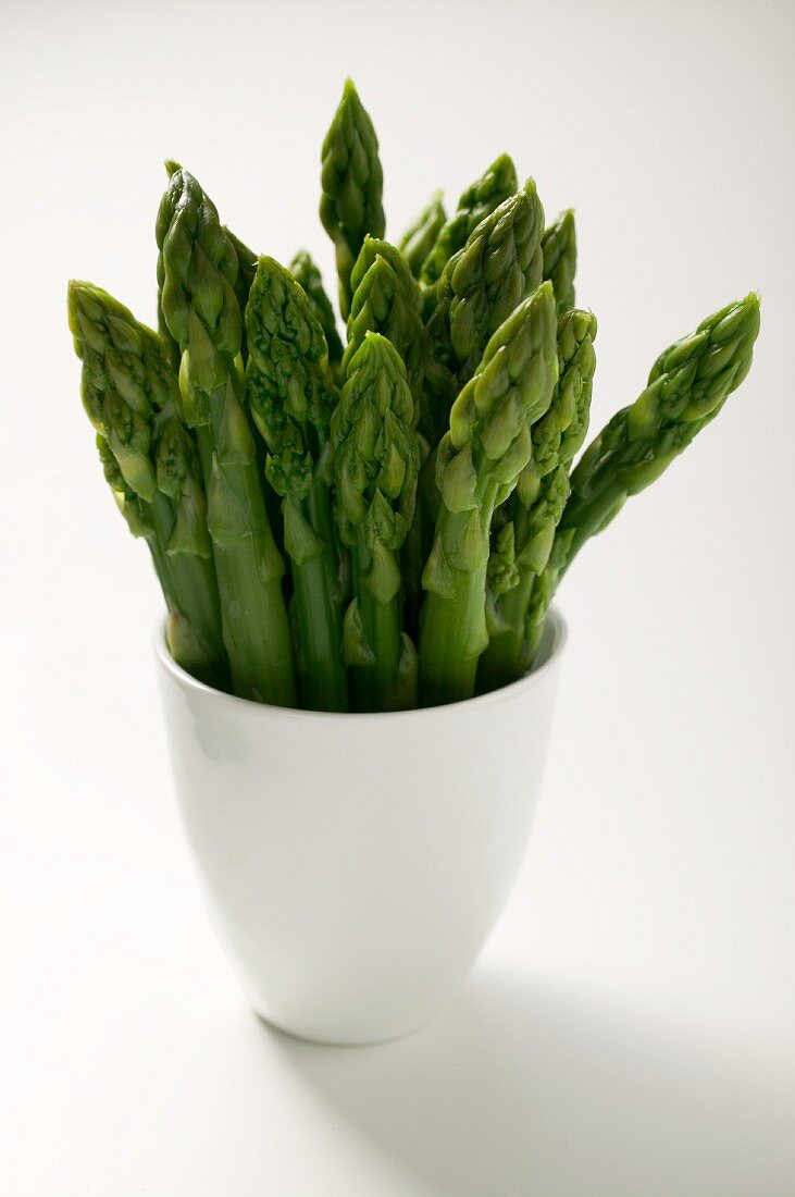 Fresh green asparagus in a white cup