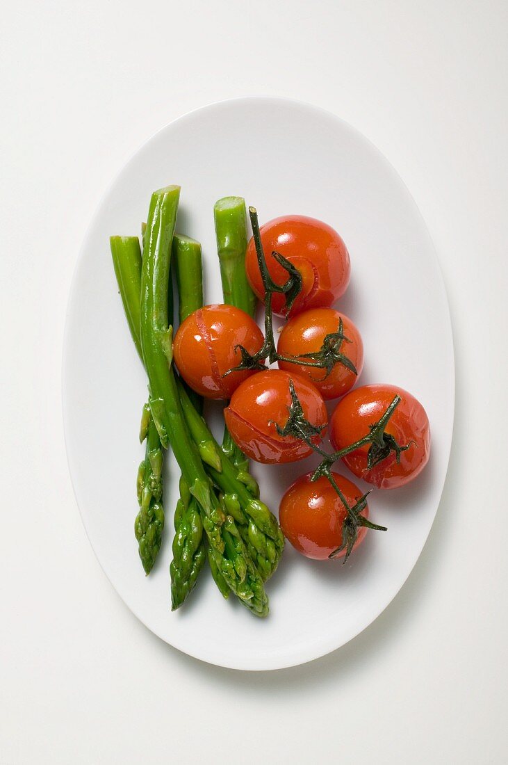 Blanched cherry tomatoes and green asparagus on a plate