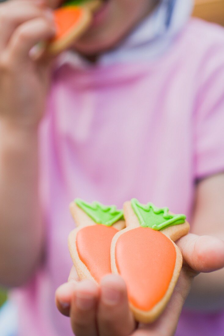 A child holding carrot biscuits