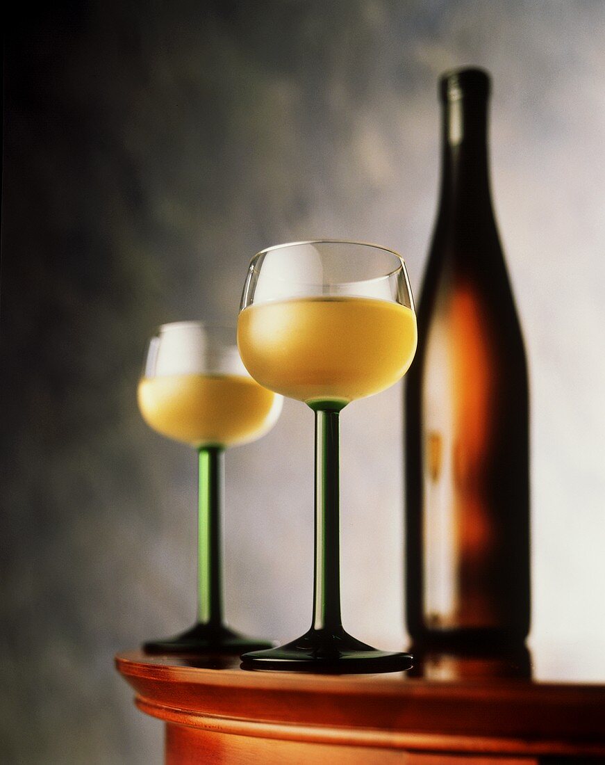 Zwei Gläser Weißwein neben einer Weinflasche