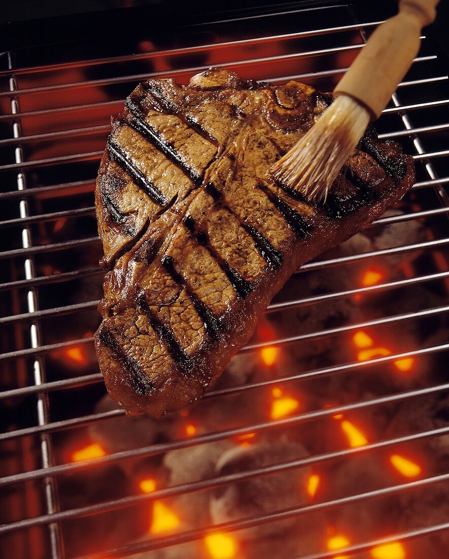 T-Bone Steak on the Grill with Barbecue Brush
