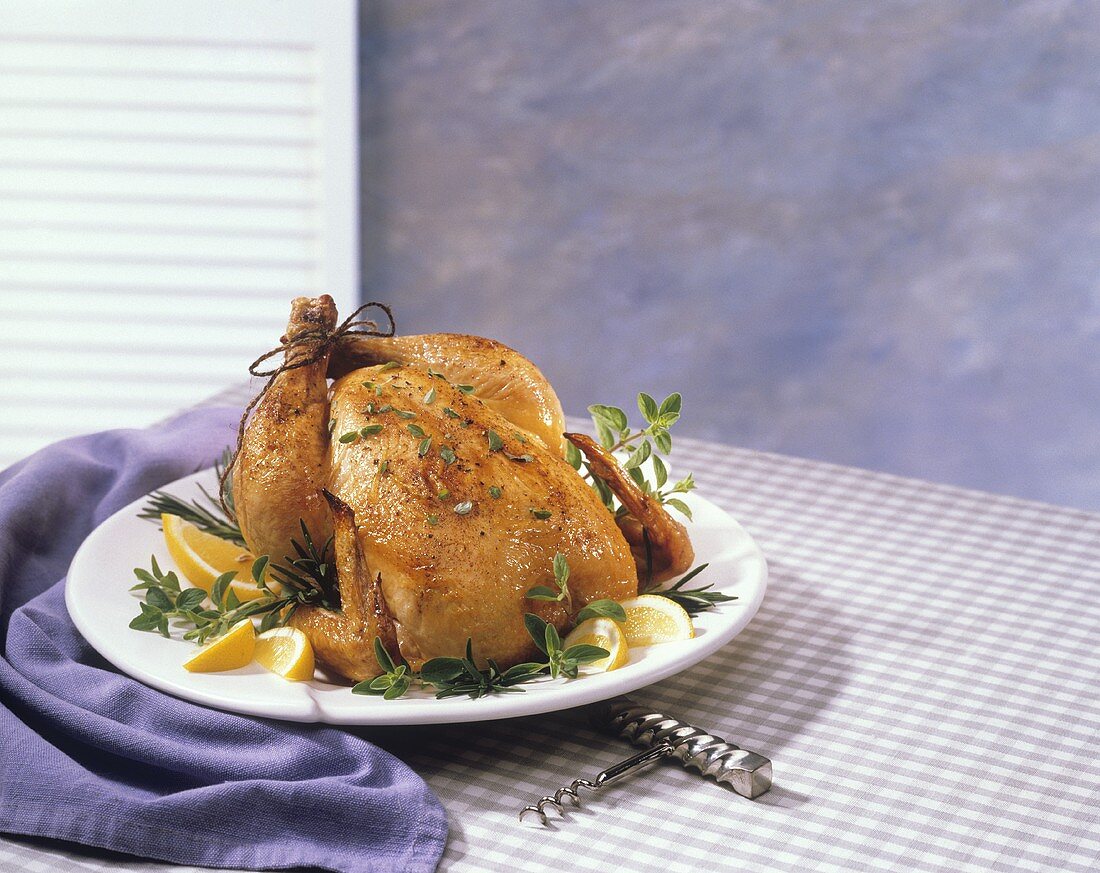 Roast Chicken with Fresh Herbs on a Platter; Corkscrew