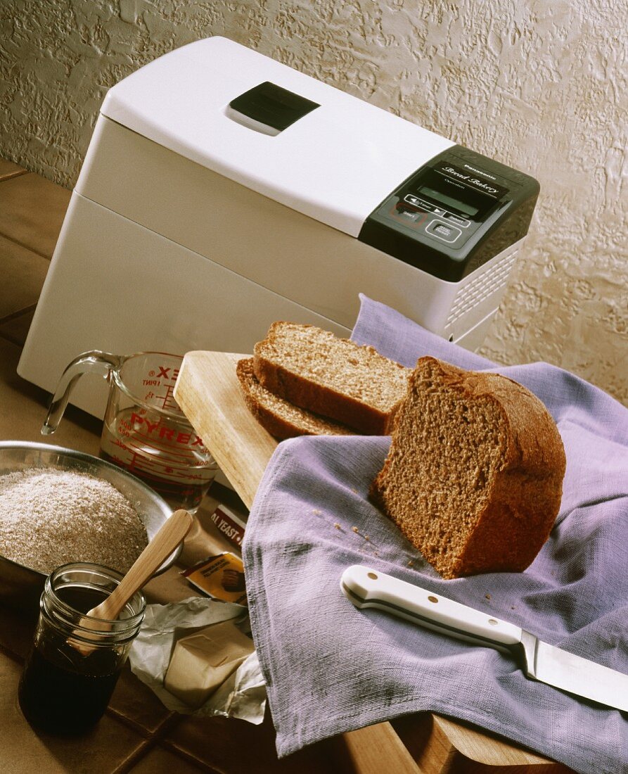 Frisch gebackenes Brot neben Brotbackmaschine und Zutaten