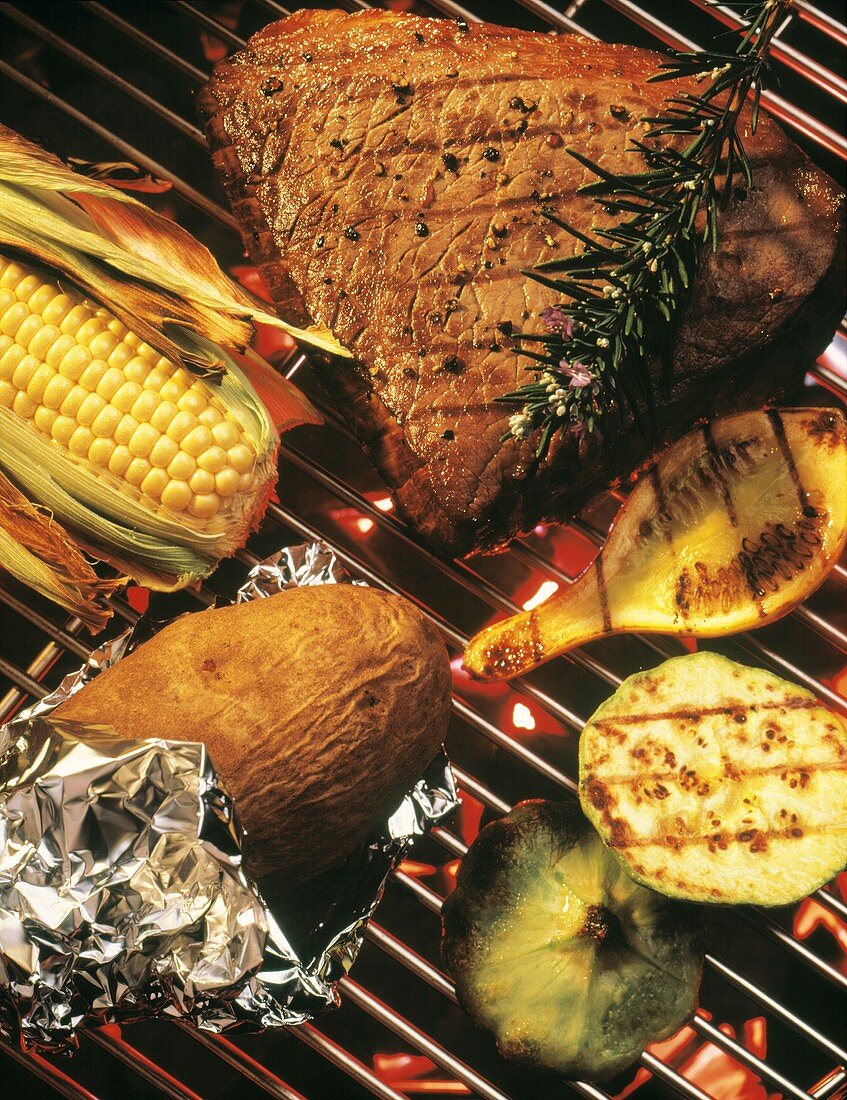 Rindersteak, Gemüse und Folienkartoffel auf dem Grill