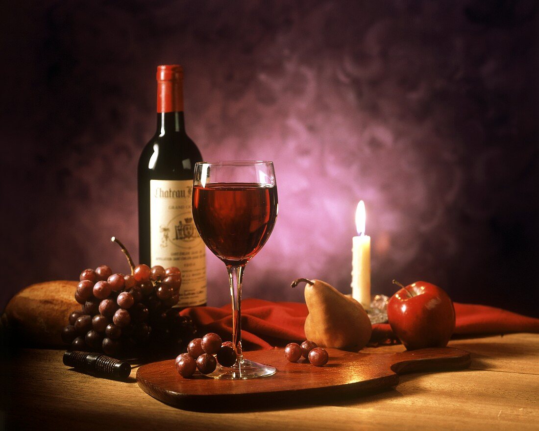 Rotwein und Obst bei Kerzenlicht