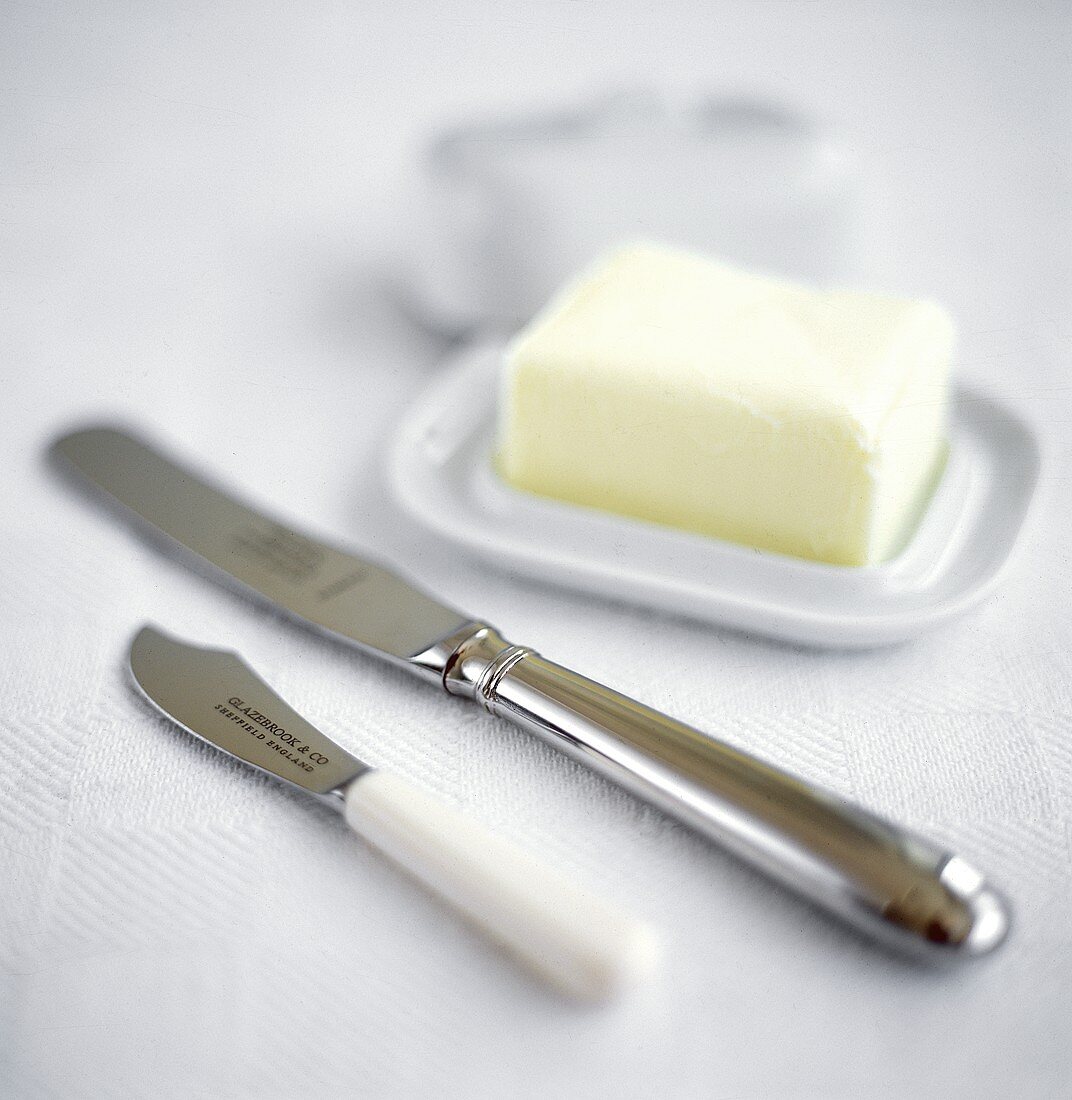 Butter auf Butterdose, daneben Messer und Buttermesser