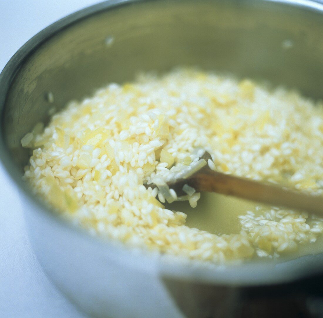 Risotto zubereiten: Reis mit Kochlöffel im Topf rühren