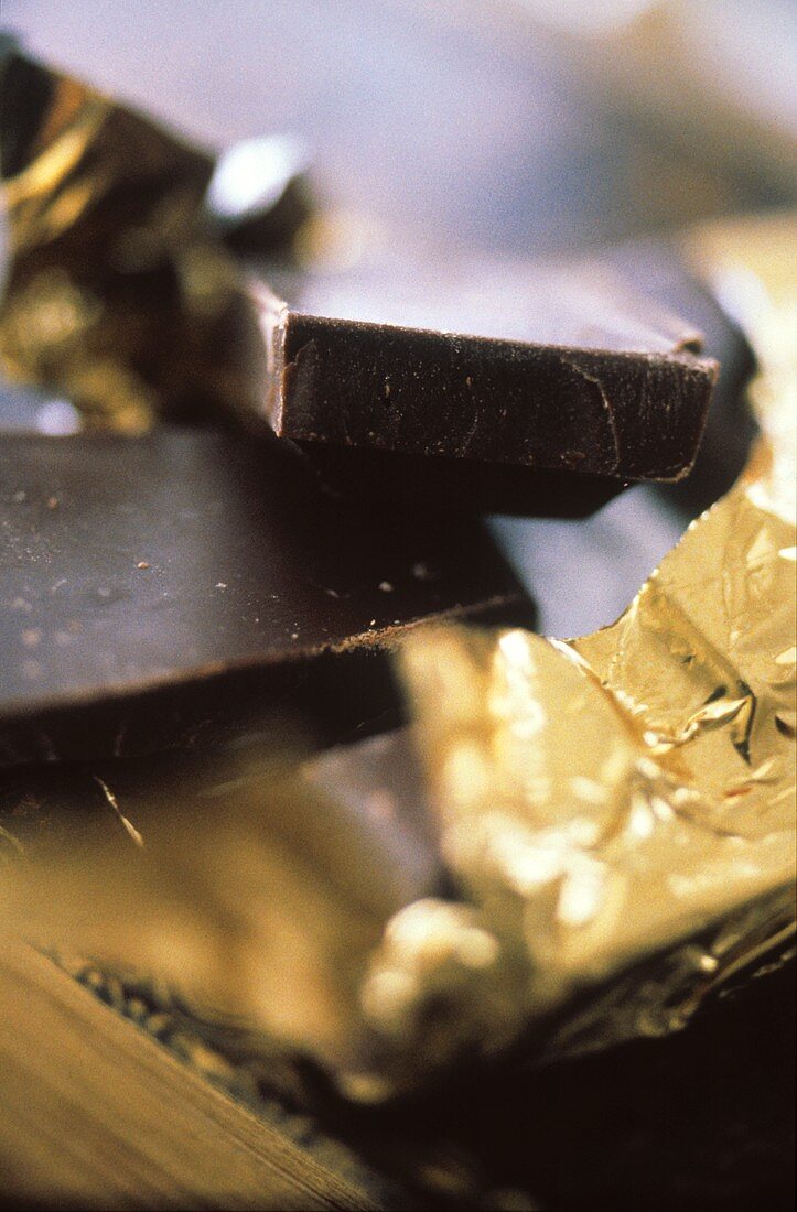 Stücke einer zerbrochenen Schokoladentafel in Goldfolie