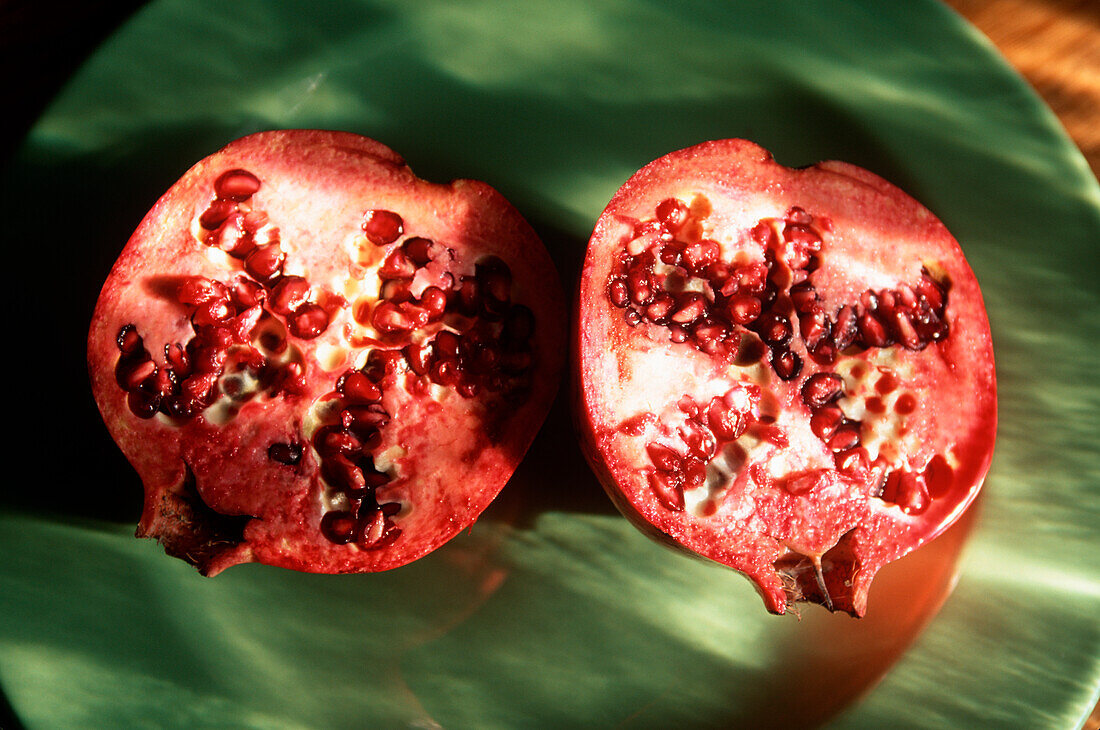 Zwei Granatapfelhälften auf grünem Teller
