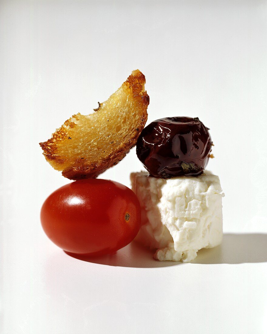 Ein Stück Knoblauchbrot, Feta, Olive und Tomate