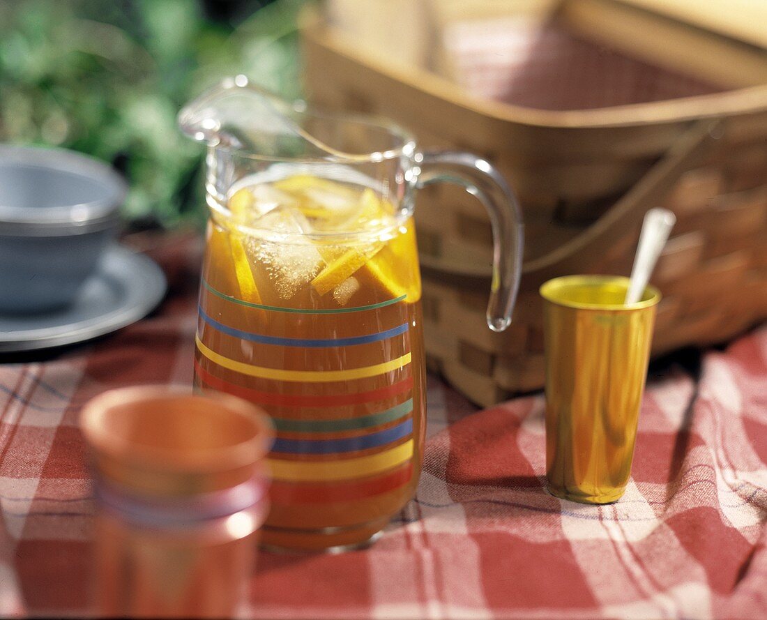 A Pitcher of Iced Tea by a Picnic Basket