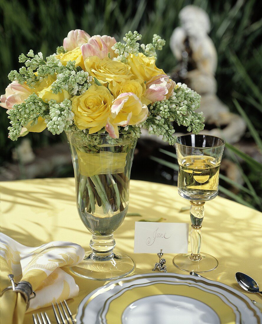 Frühsommerlich gedeckter Tisch mit gelben Rosen und Weißwein