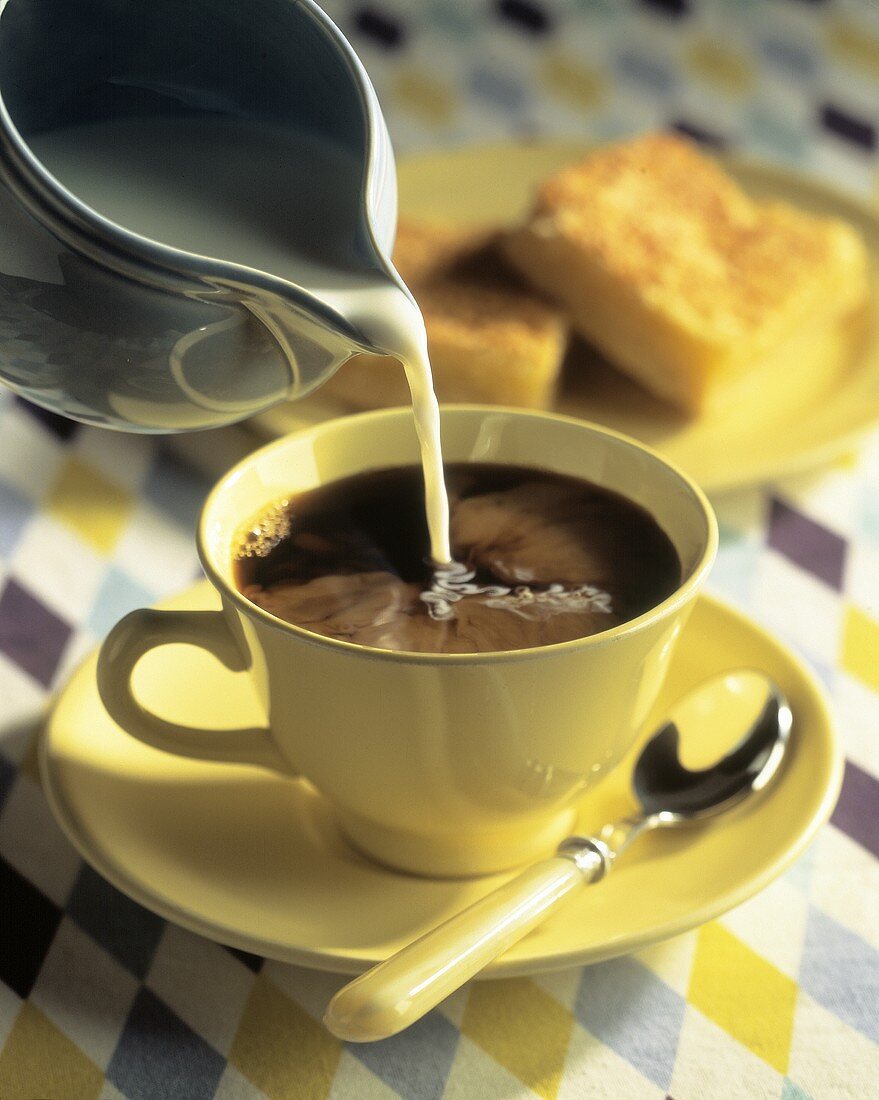 Milch in Kaffeetasse gießen