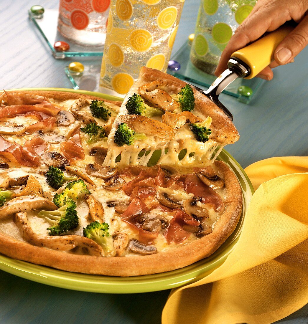 Pizza with chicken, ham & broccoli with piece on server
