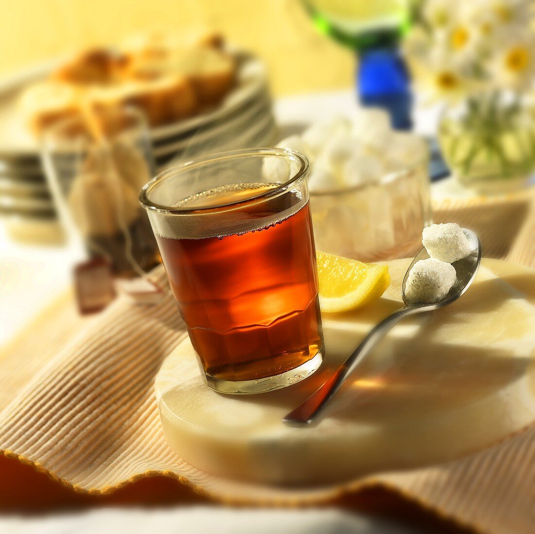 Heisser Tee im Glas mit Zitrone und Zuckerwürfeln