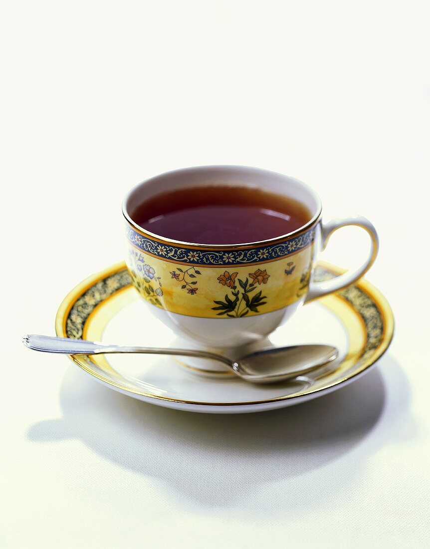 Tee in gelber Tasse mit Blumendeko