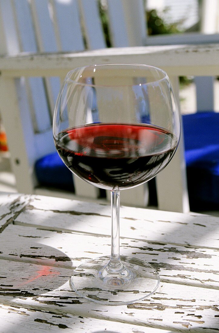 Glas Rotwein auf Tisch im Freien