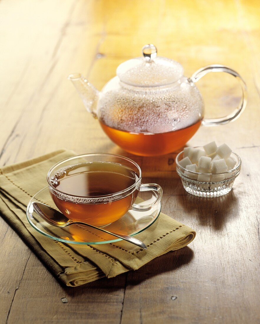 Tee in Glaskanne und Glastasse; Zuckerwürfel