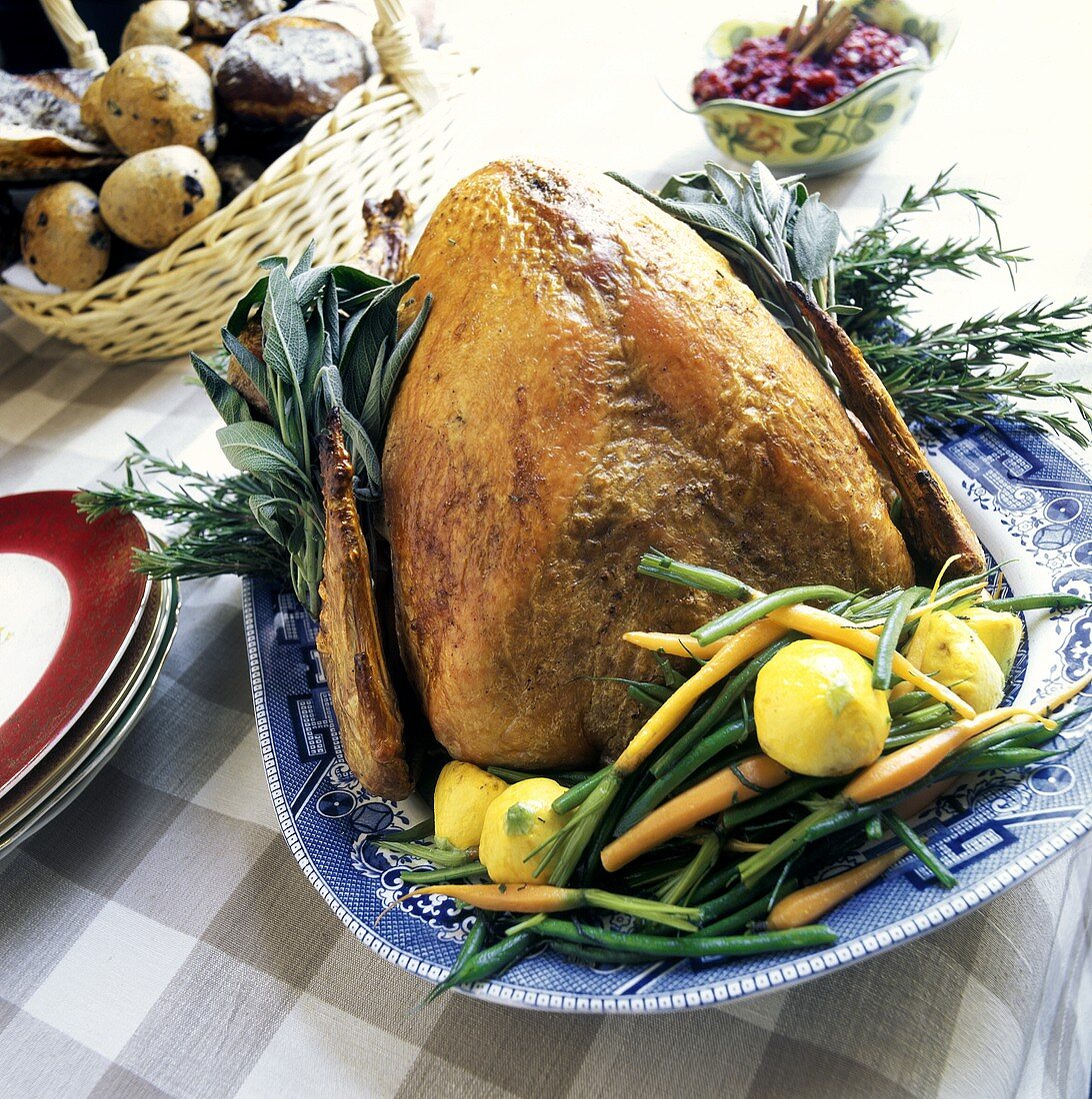 A Whole Roast Turkey on a Platter Garnished with Herbs and Fresh Vegetables