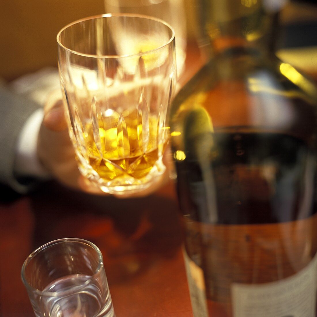 Hand hält Glas Whiskey in einer Bar