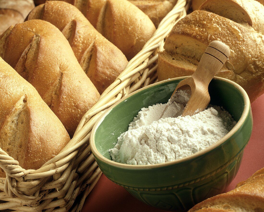 Loaves of Bread in Basket with a Bowl of Flour and Scoop in the Bowl