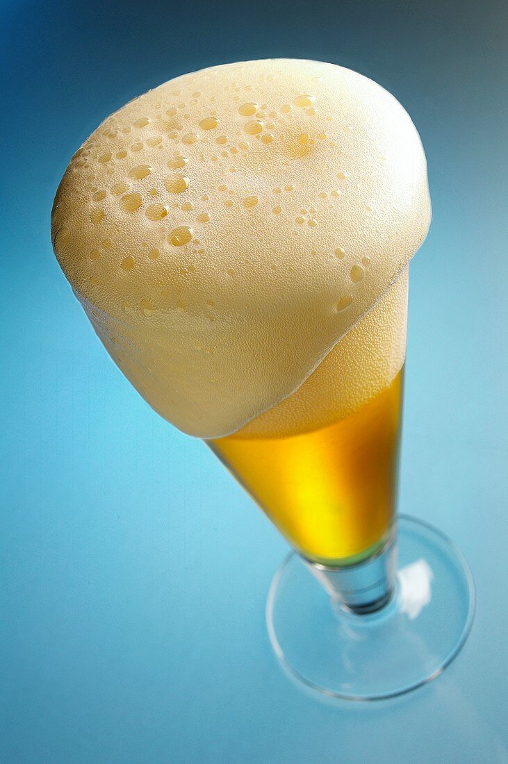 Überschäumendes helles Bier im Glas