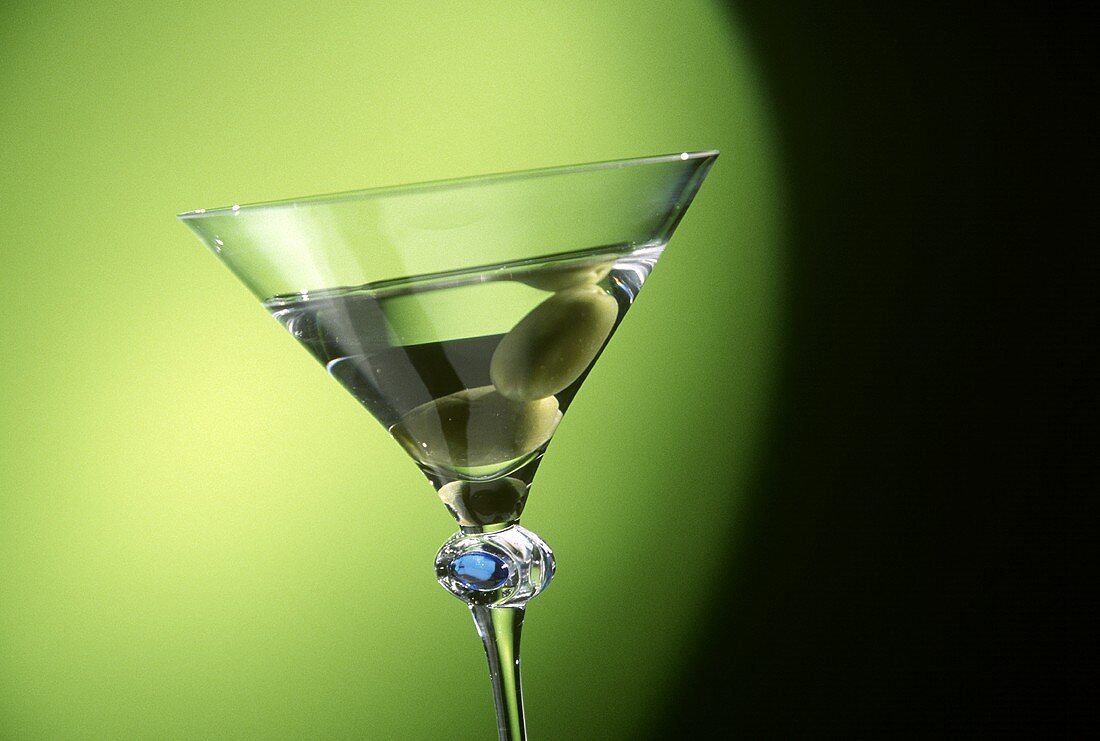 Glas Martini mit zwei Oliven vor grünem Hintergrund (Detail)