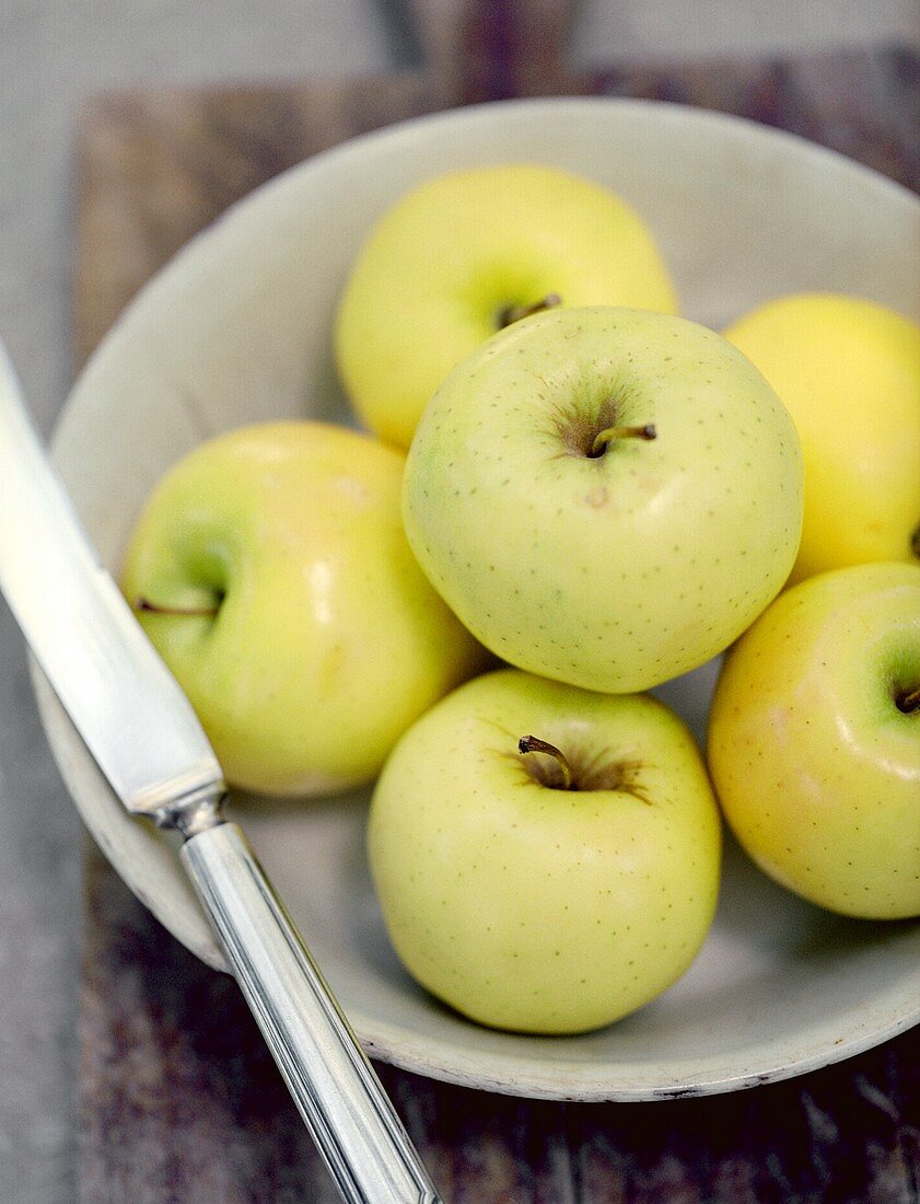 A Bowl of Golden Delicious Apples with Knife