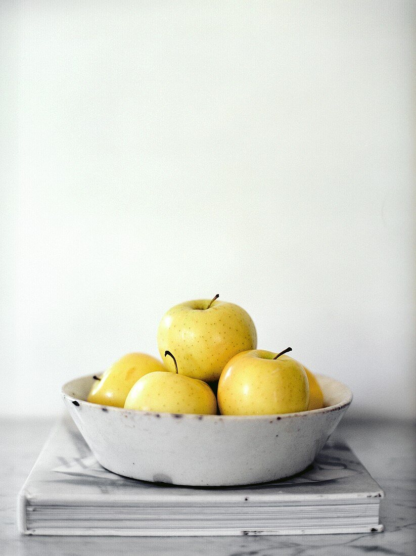 A Bowl of Golden Delicious Apples on a Book