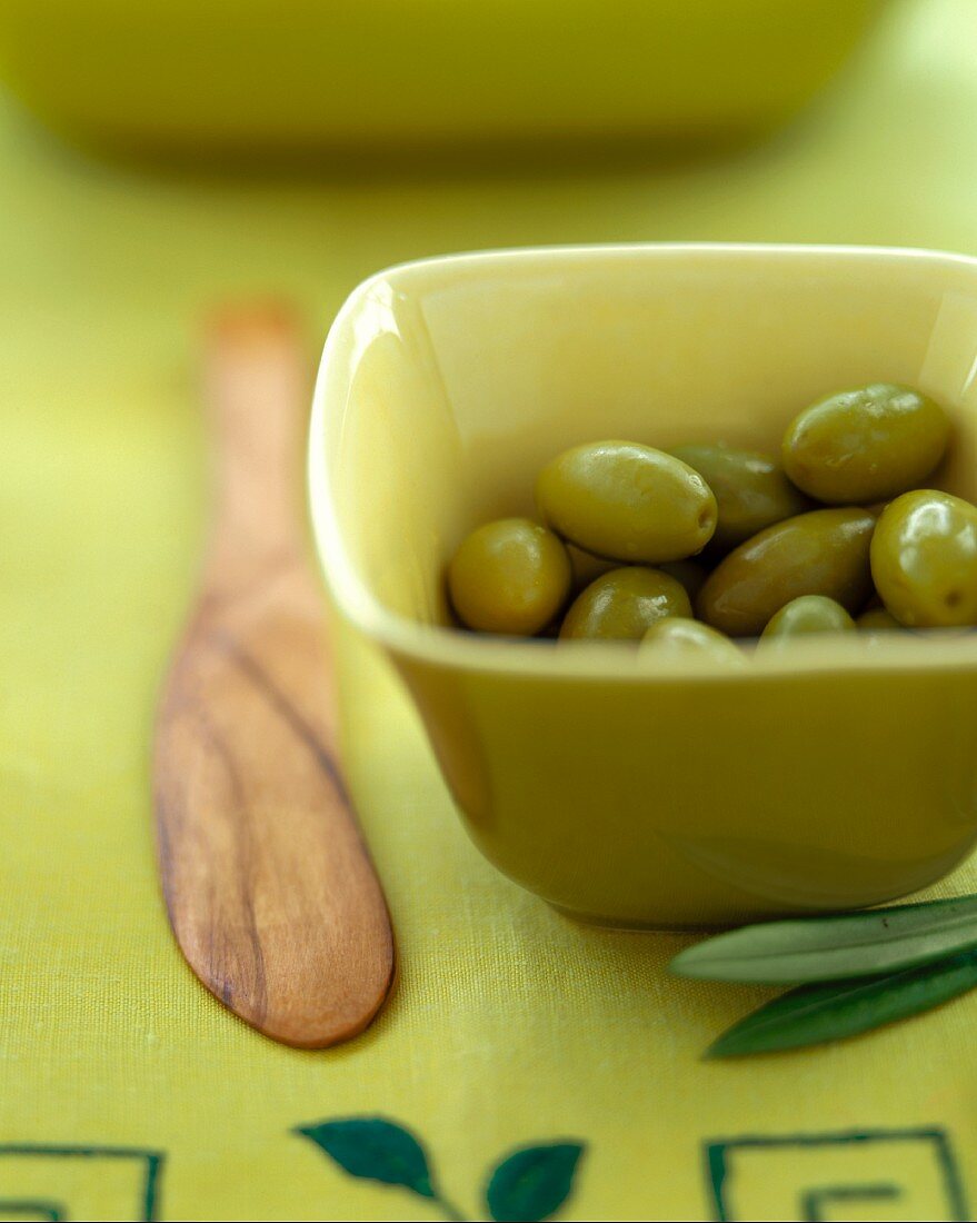 Green olives in a square, green bowl