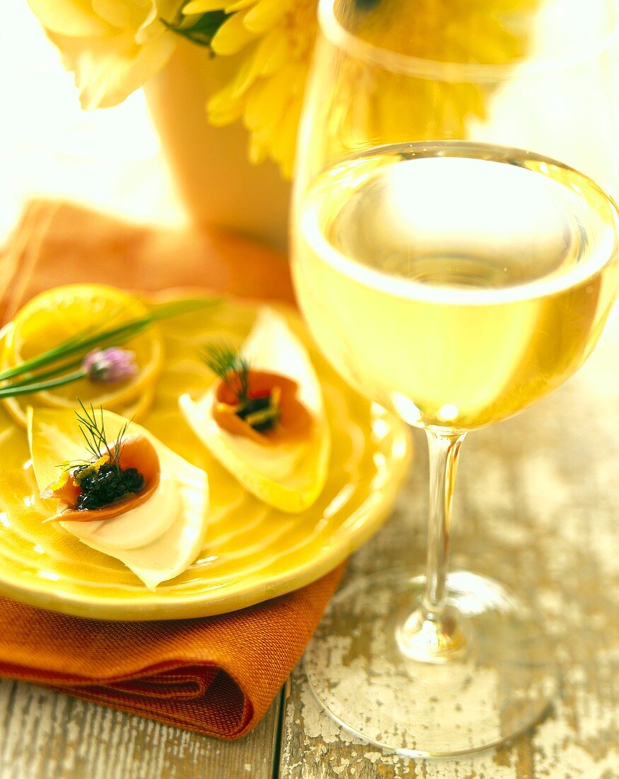 Chicoreeblätter mit Kaviar; Glas Weißwein