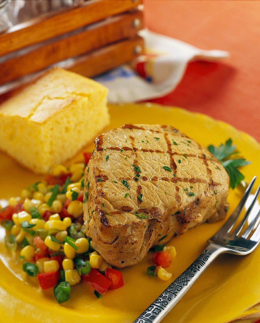 A grilled pork steak with vegetables and bread