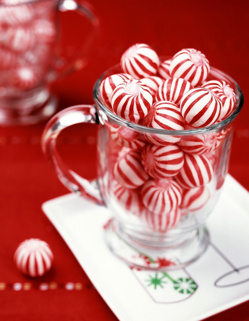 Red and white peppermint sweets in a glass mug