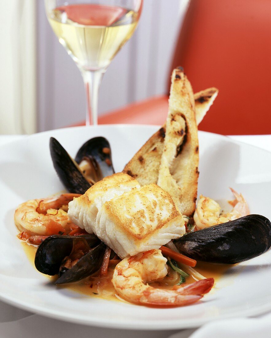 Cod fillet with shrimps and mussels, glass of white wine